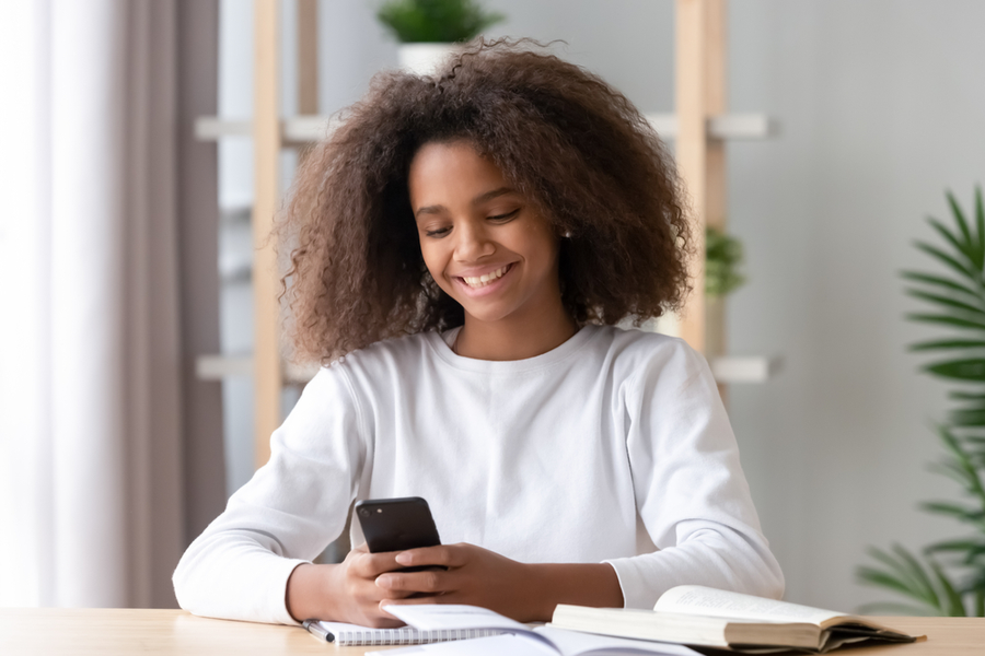 African American teen girl looking at cell phone African American teengirl looking at cell phone with a smile