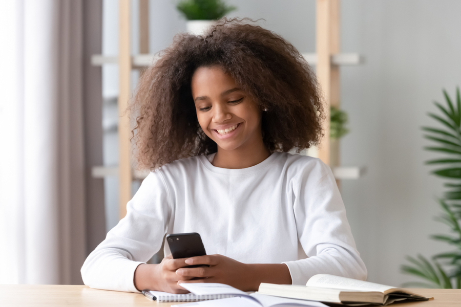 African American teengirl looking at cell phone with a smile