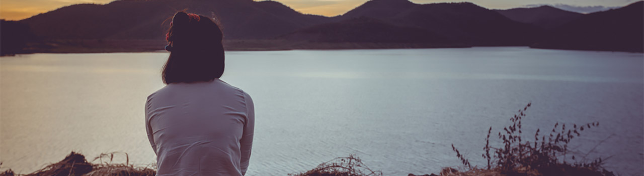 woman-gazing-at-sunset-with-mountain-backdrop